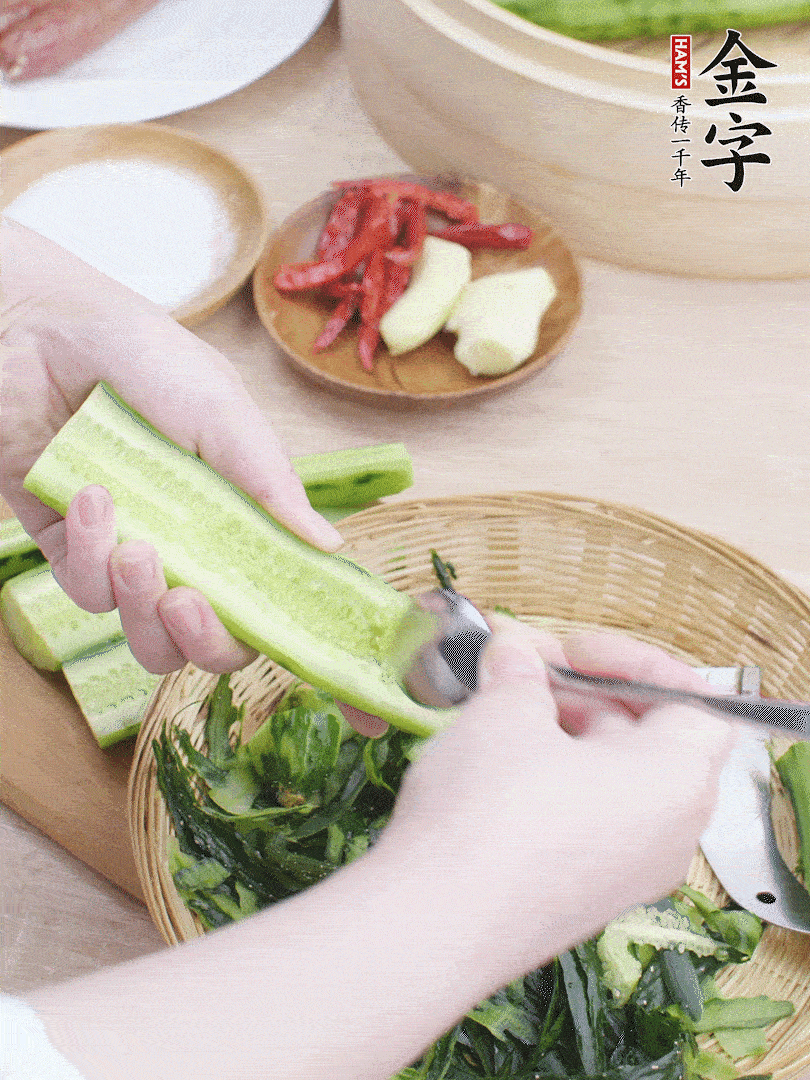 黃瓜削皮，對半切開，勺子挖去內(nèi)瓤，斜刀切片。青蒜斜刀切段。