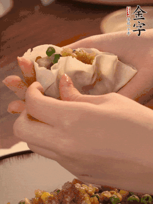 取一大勺餡料放進(jìn)餃子皮里，用大拇指按住頂部餡料，再用虎口掐出形狀。